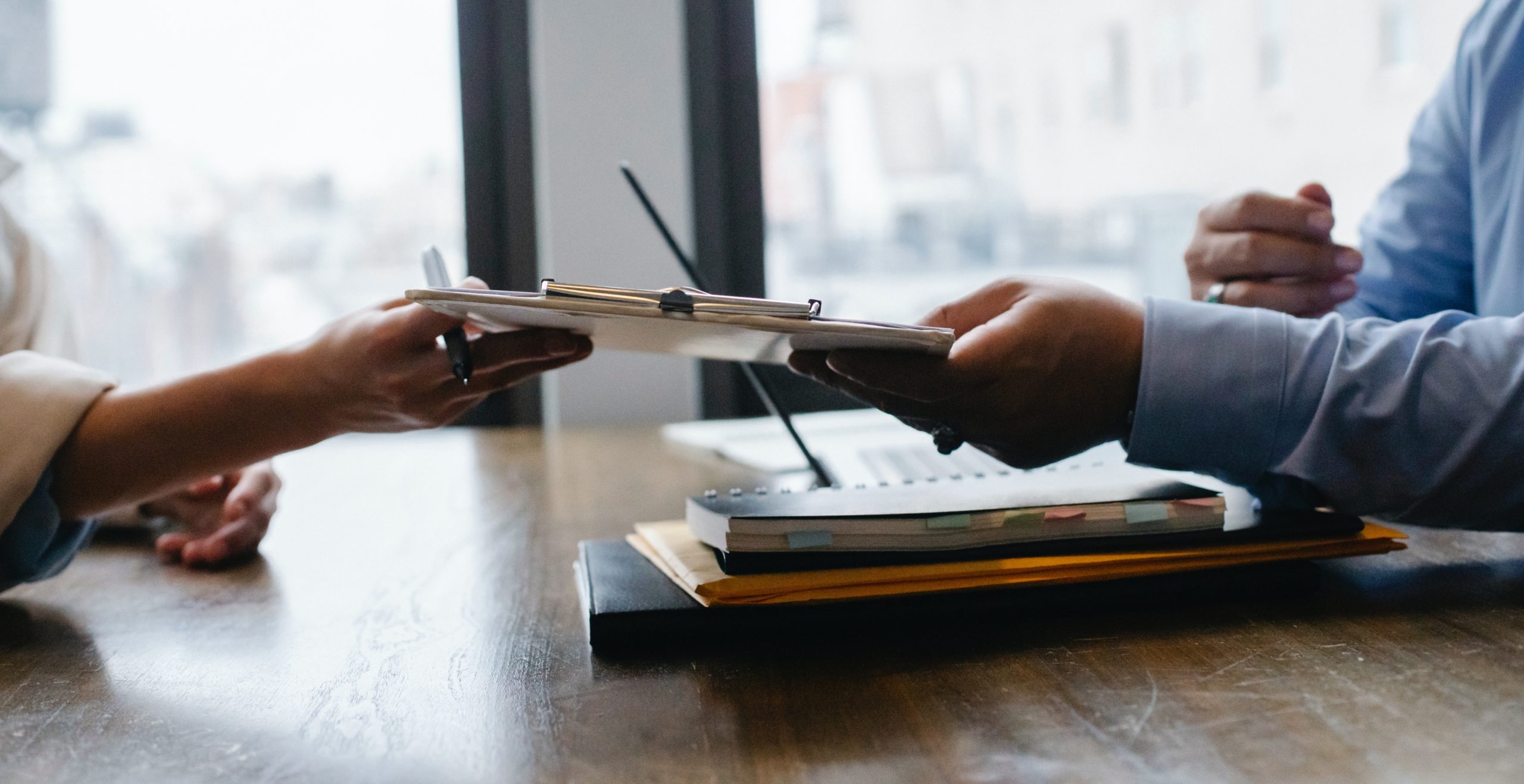 man handing clipboard to a woman and telling her that staffing factoring can help with cash flow